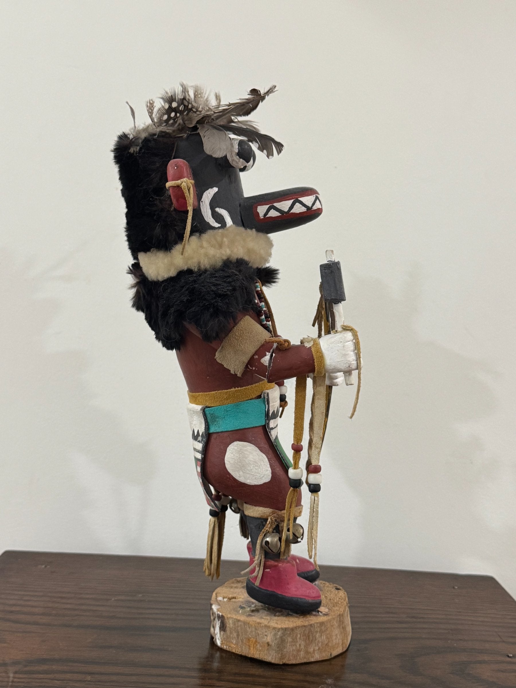 Side profile showing carved head with white spiral designs, red ears, black fur, and colorful body details
