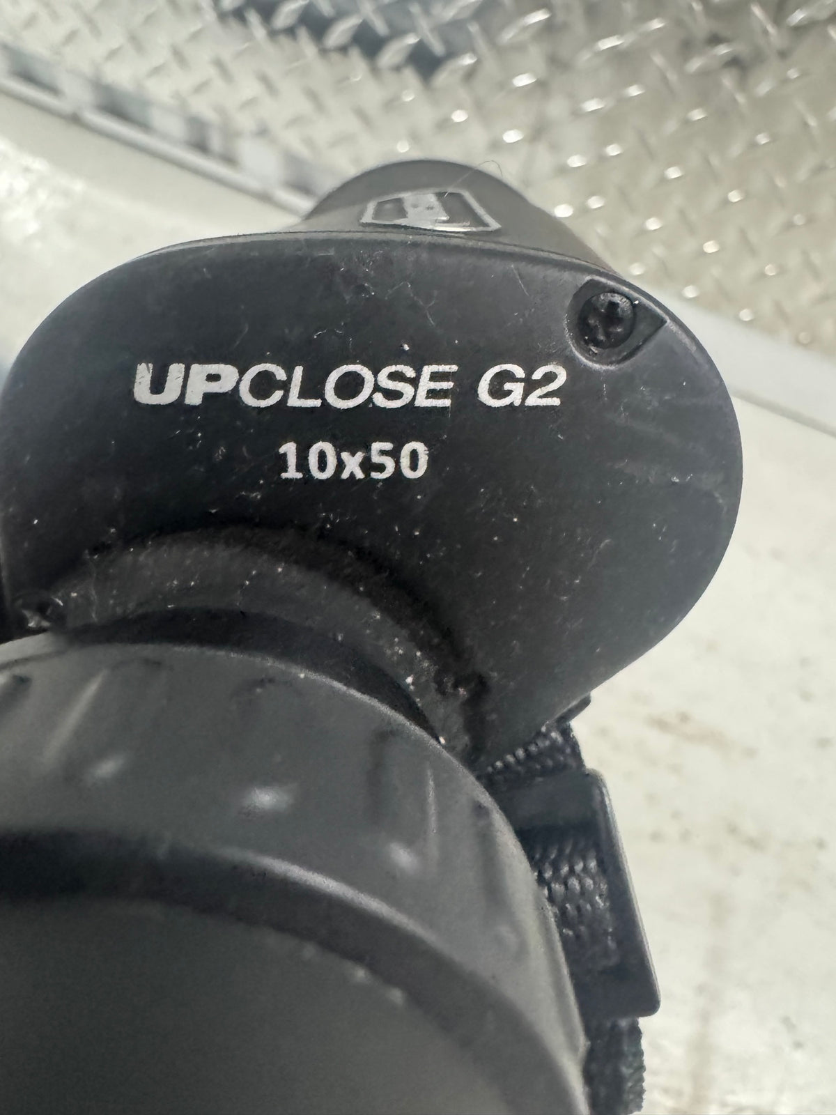 Close-up of right eyepiece showing white text reading 'UPCLOSE G2' and '10x50' on black rubber coating