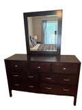 Espresso finish 7-drawer wood dresser with matching beveled mirror on top, shown in a bedroom setting