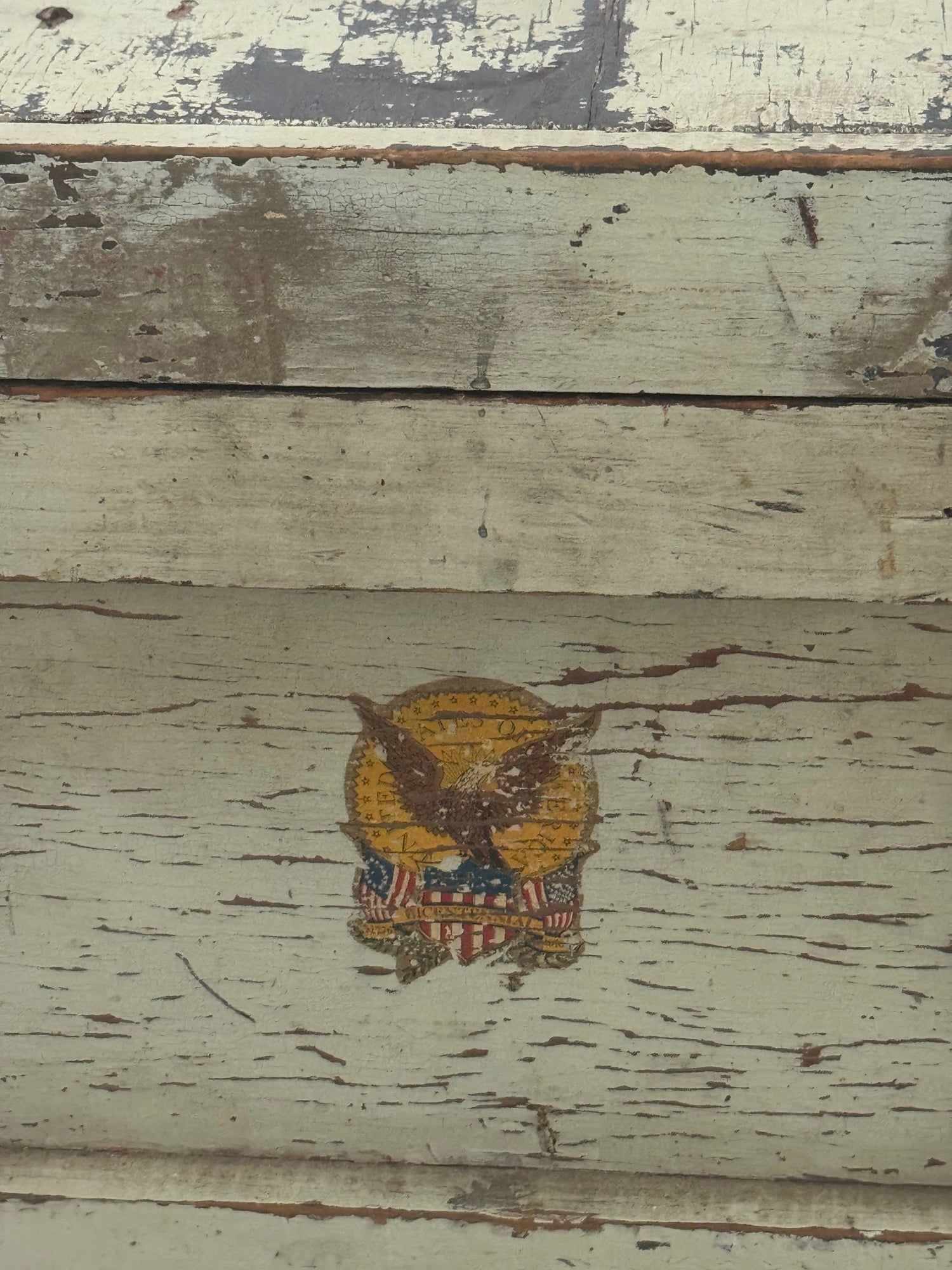 Single gold eagle decal with shield and stars, centered on cream painted wooden panel with visible wear and distressing
