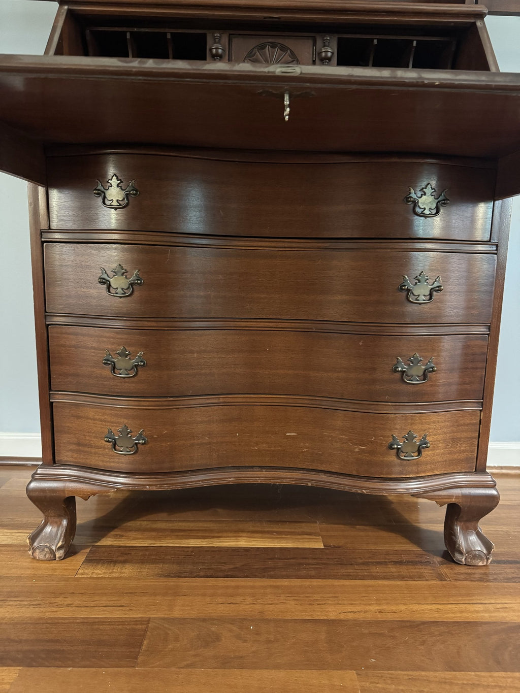 Serpentine four-drawer base with brass pulls and ball-and-claw feet