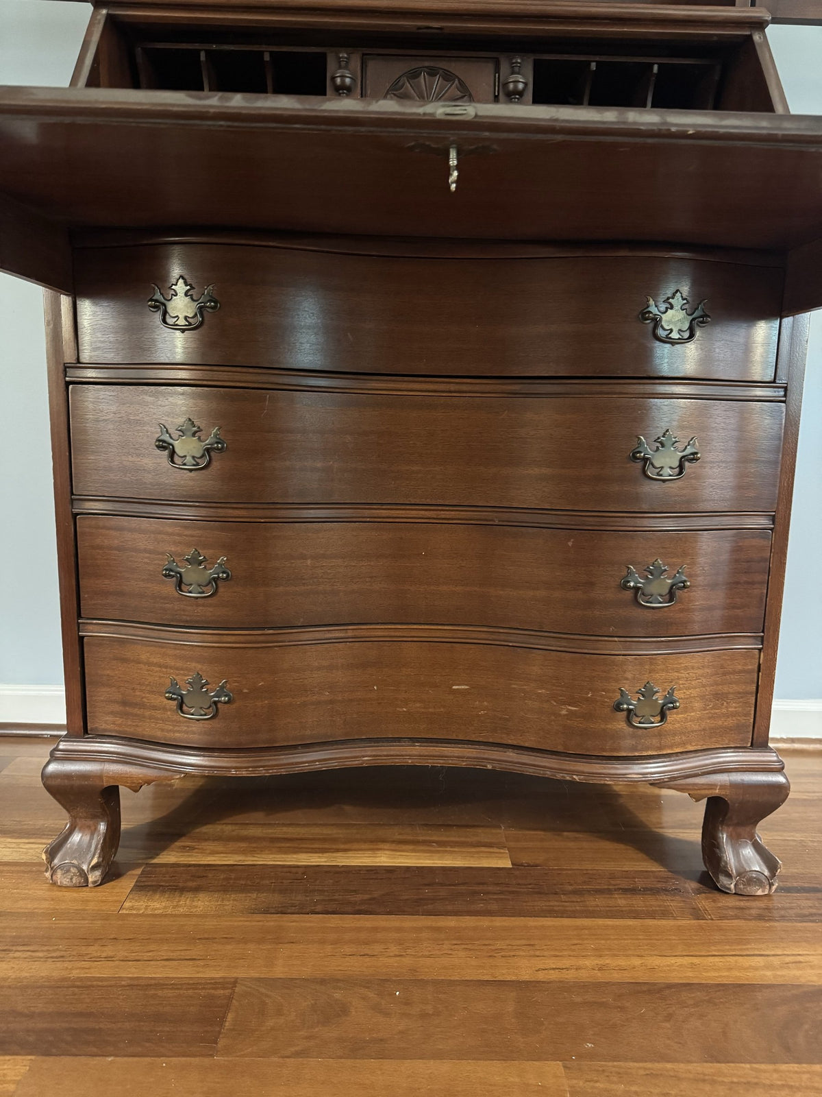 Serpentine four-drawer base with brass pulls and ball-and-claw feet