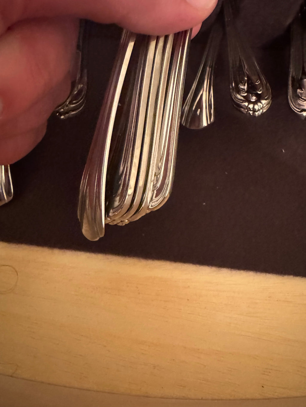Close-up of stacked fork handles including two with darker tarnish spotting