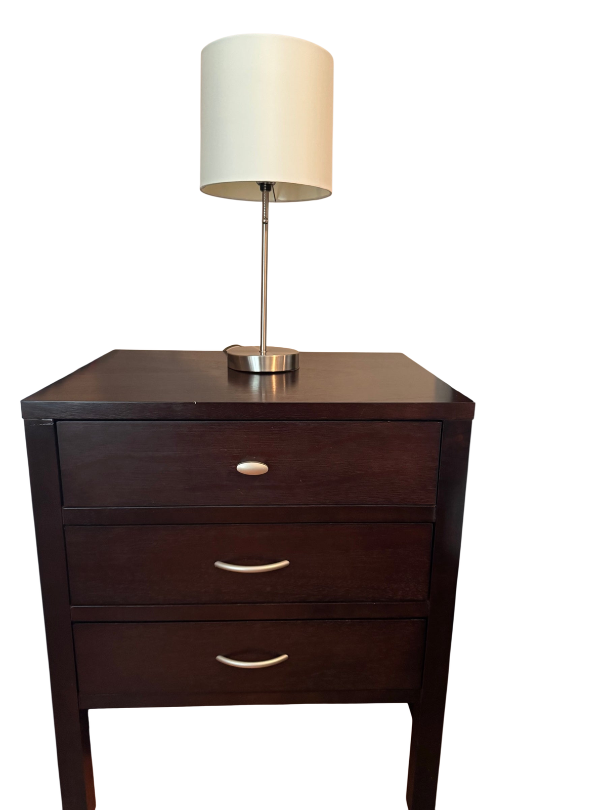 Espresso finish three-drawer nightstand with brushed nickel bar pulls, positioned beside a bed with a lamp on top.