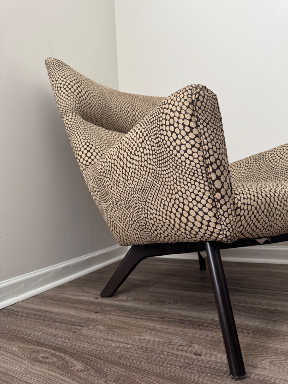 Side profile of chair showing curved arm and dark wooden leg