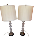 Pair of tall table lamps with clear ball stems and off-white drum shades, front view