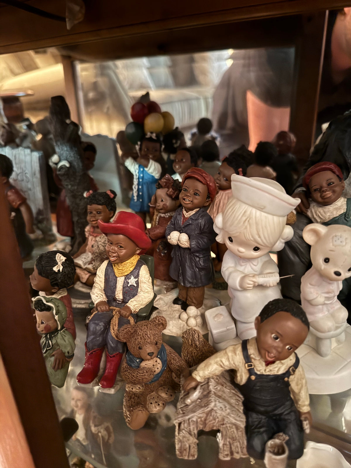Close view of figurines including a boy in a red cowboy hat, a boy in a coat with snowballs, and a nurse figurine