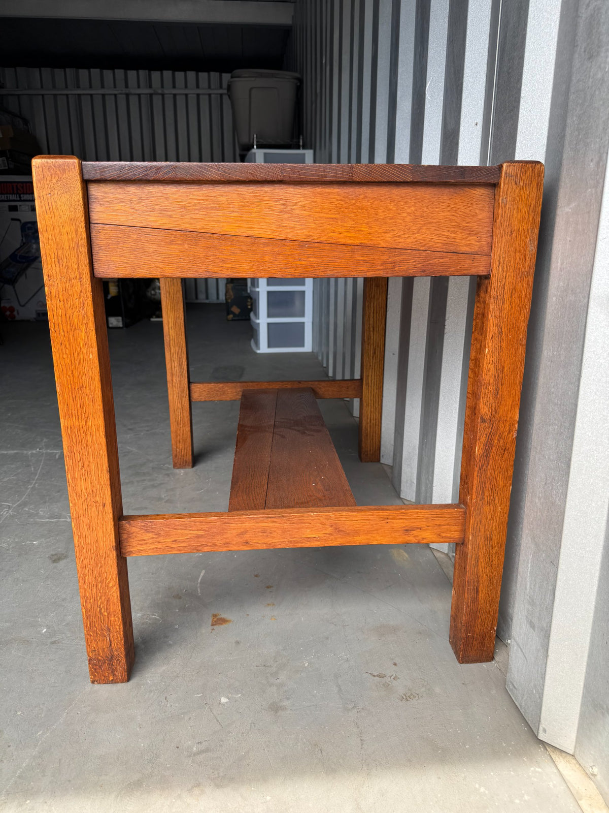 Side table viewed from behind in outdoor setting, showing back panel construction and lower shelf support structure