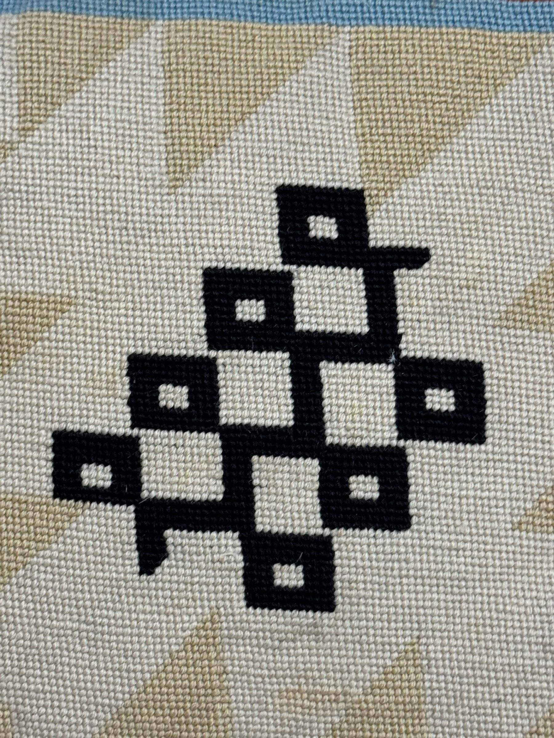 Close-up of black and white geometric diamond pattern with cream background and tan quilted detail