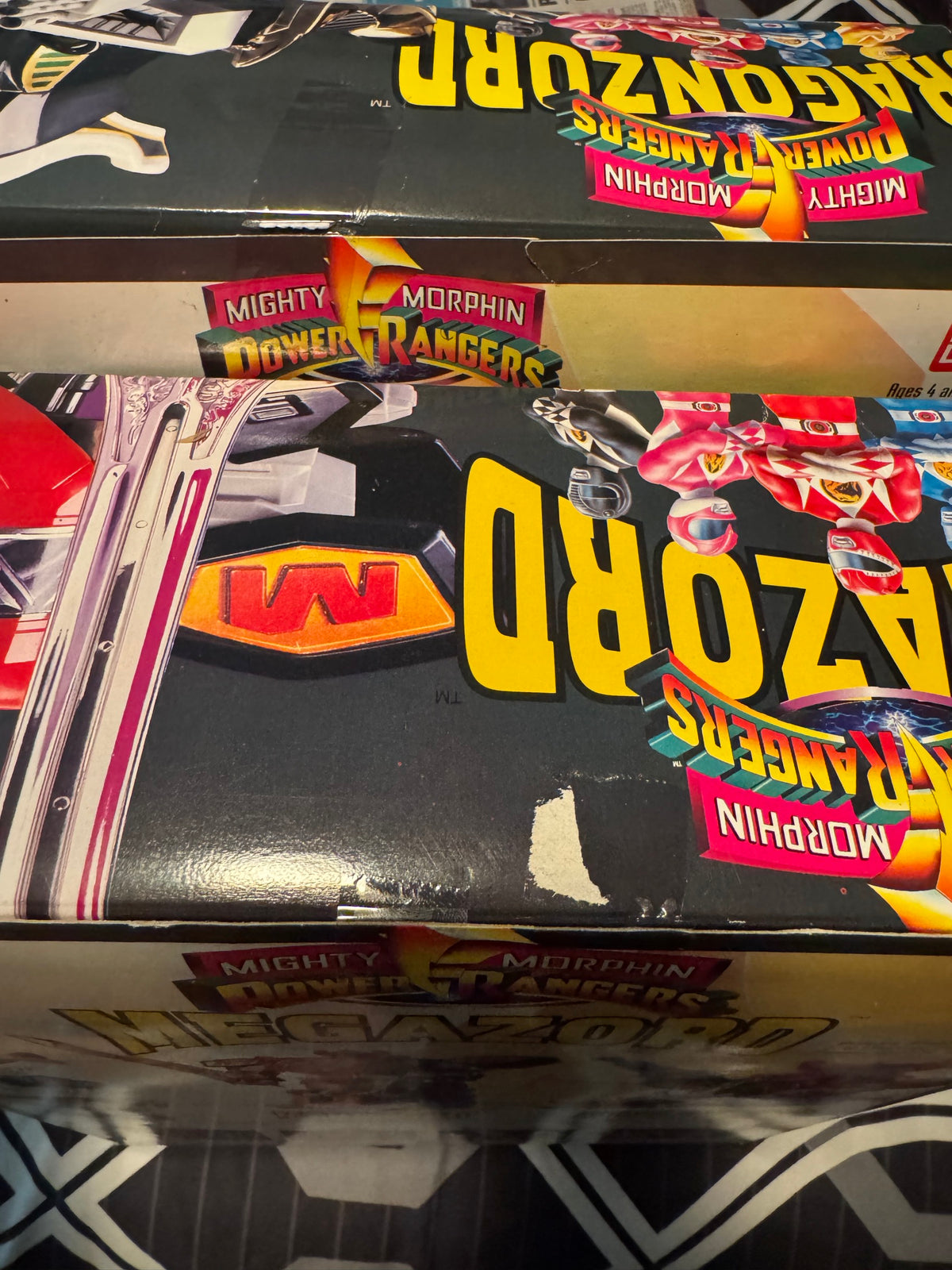 Side view of stacked Dragonzord and Megazord boxes showing logos