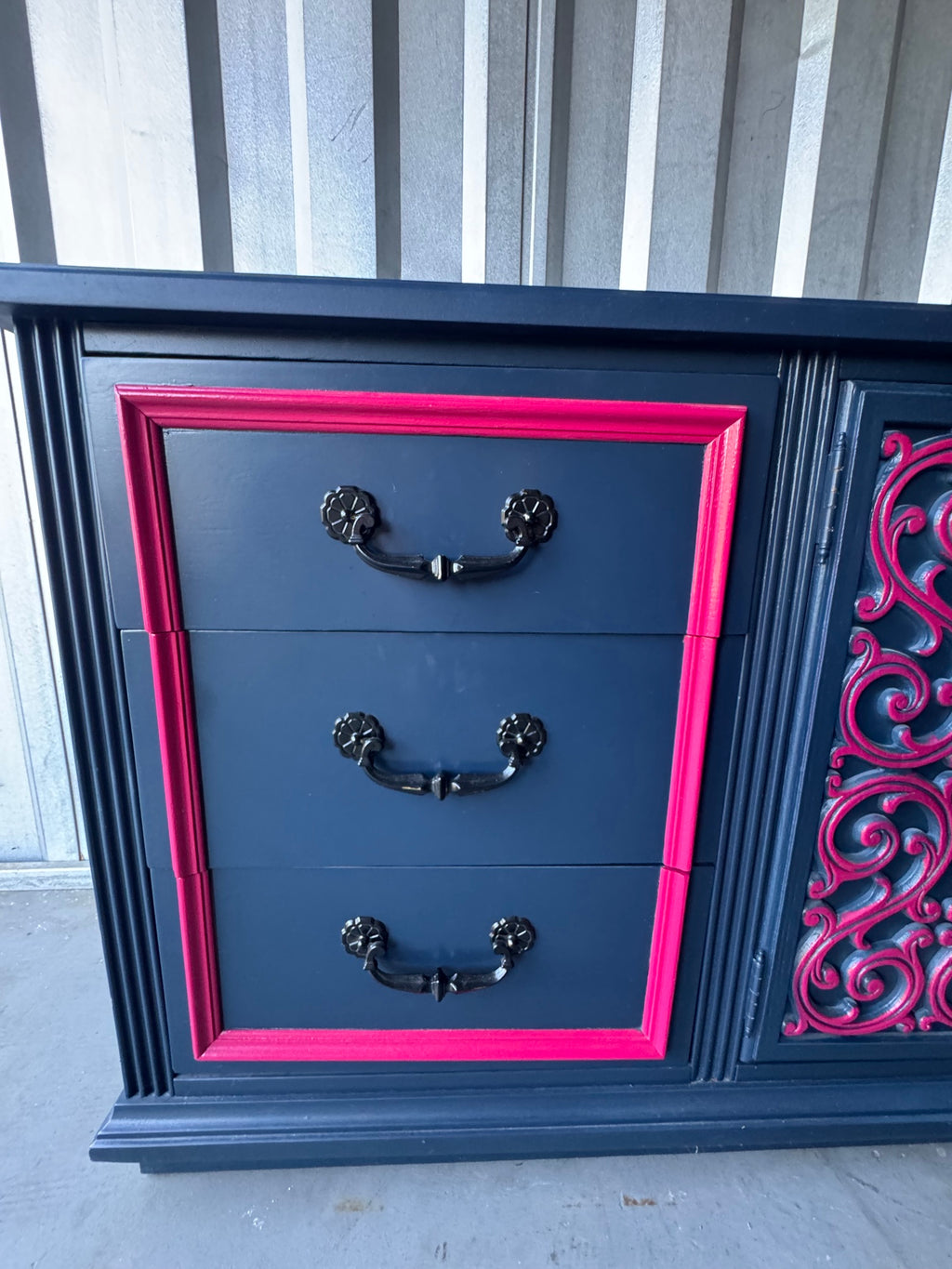 Detail of right drawer section showing three navy drawers with pink border frame and black ornate handles