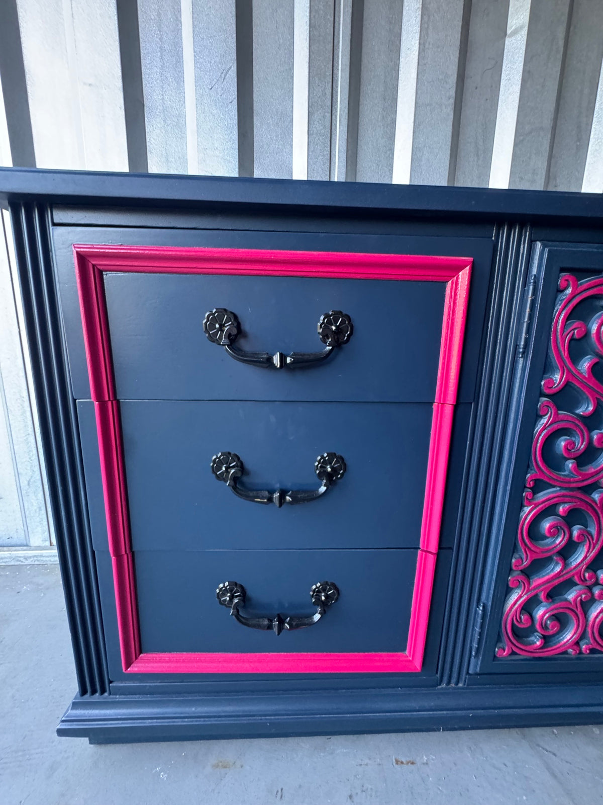 Detail of right drawer section showing three navy drawers with pink border frame and black ornate handles