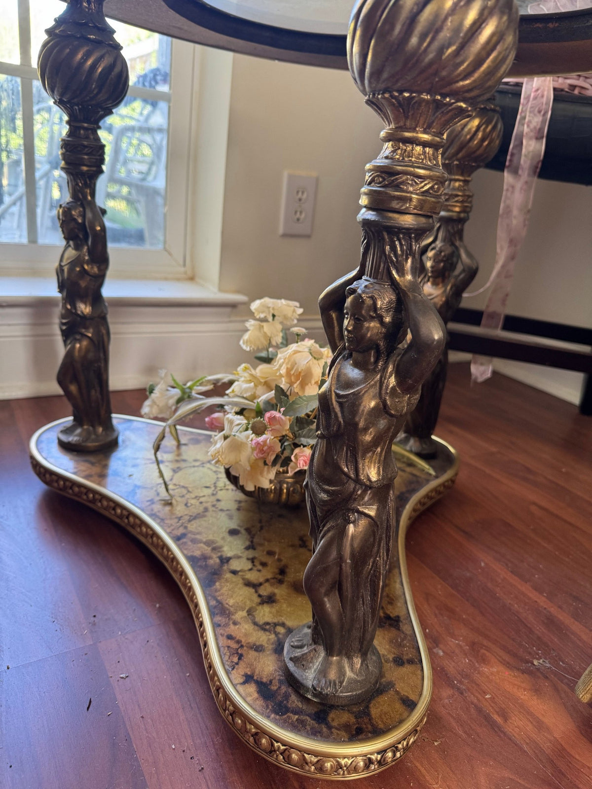 Figural support columns standing on the gilt three-lobed base