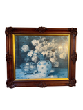 Framed still life print of white tulips in a blue and white vase, set in an ornate carved wood frame with gold gilt liner, hanging on a wall