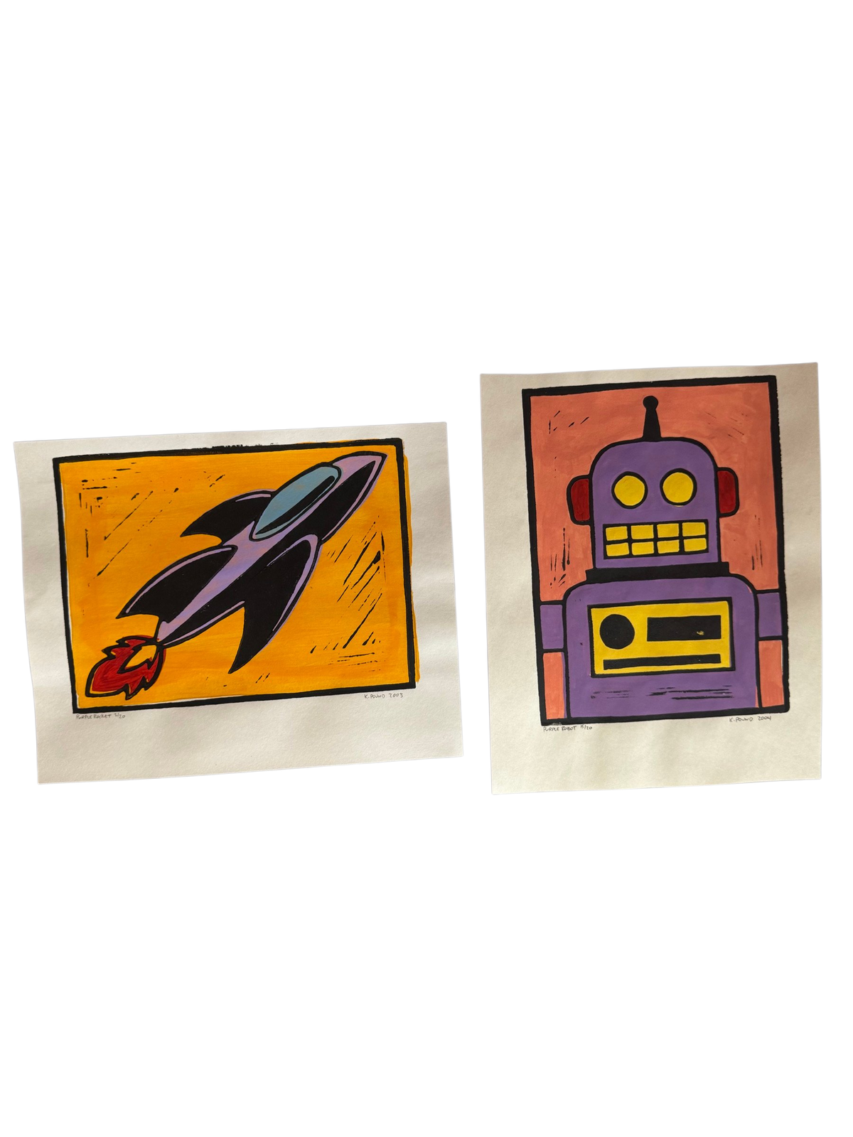 Pair of hand-colored linocuts, rocket and robot, side by side on a grey cloth