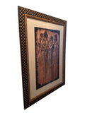 Angled view of a framed sepia-toned print of four African women in a black and gold checkerboard frame, hanging on a wall