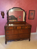 Antique walnut dresser with mirror viewed from front, showing decorative veneered drawer fronts with geometric inlay and turned finials