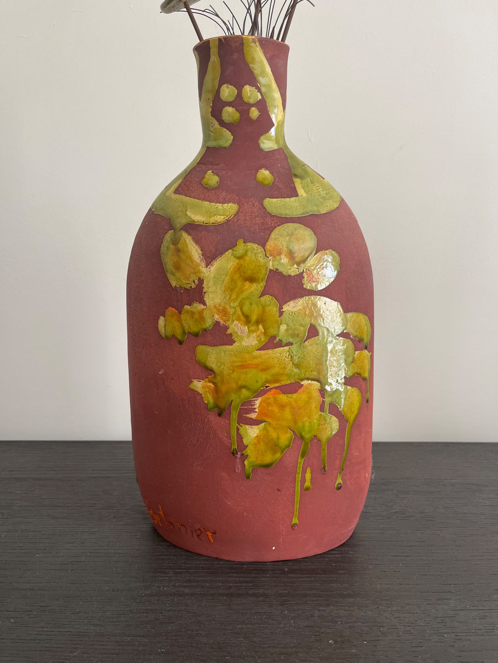 Front view of complete vase with metal stems displaying orange, red, and brown painted leaf forms and natural wood disc accents