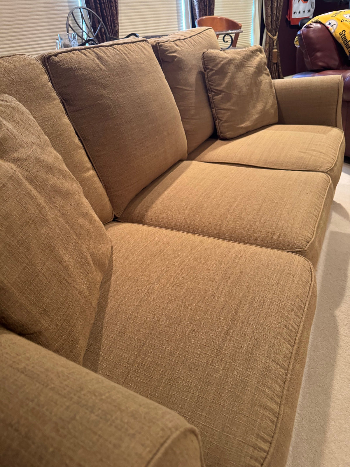 Close-up of left side arm and cushions showing tan linen upholstery texture and seaming detail
