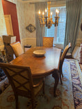 Formal dining room with wooden table, four upholstered chairs, ornate gold chandelier, floral wallpaper