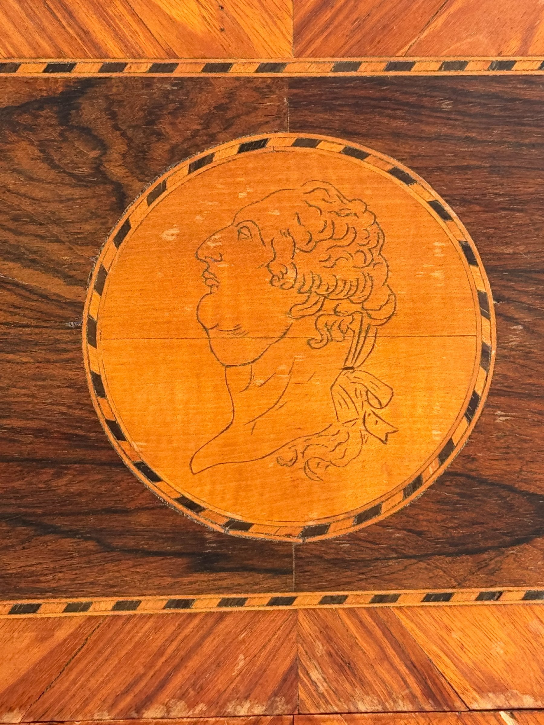 Close-up of circular marquetry medallion on drawer front depicting classical profile portrait with decorative inlay border