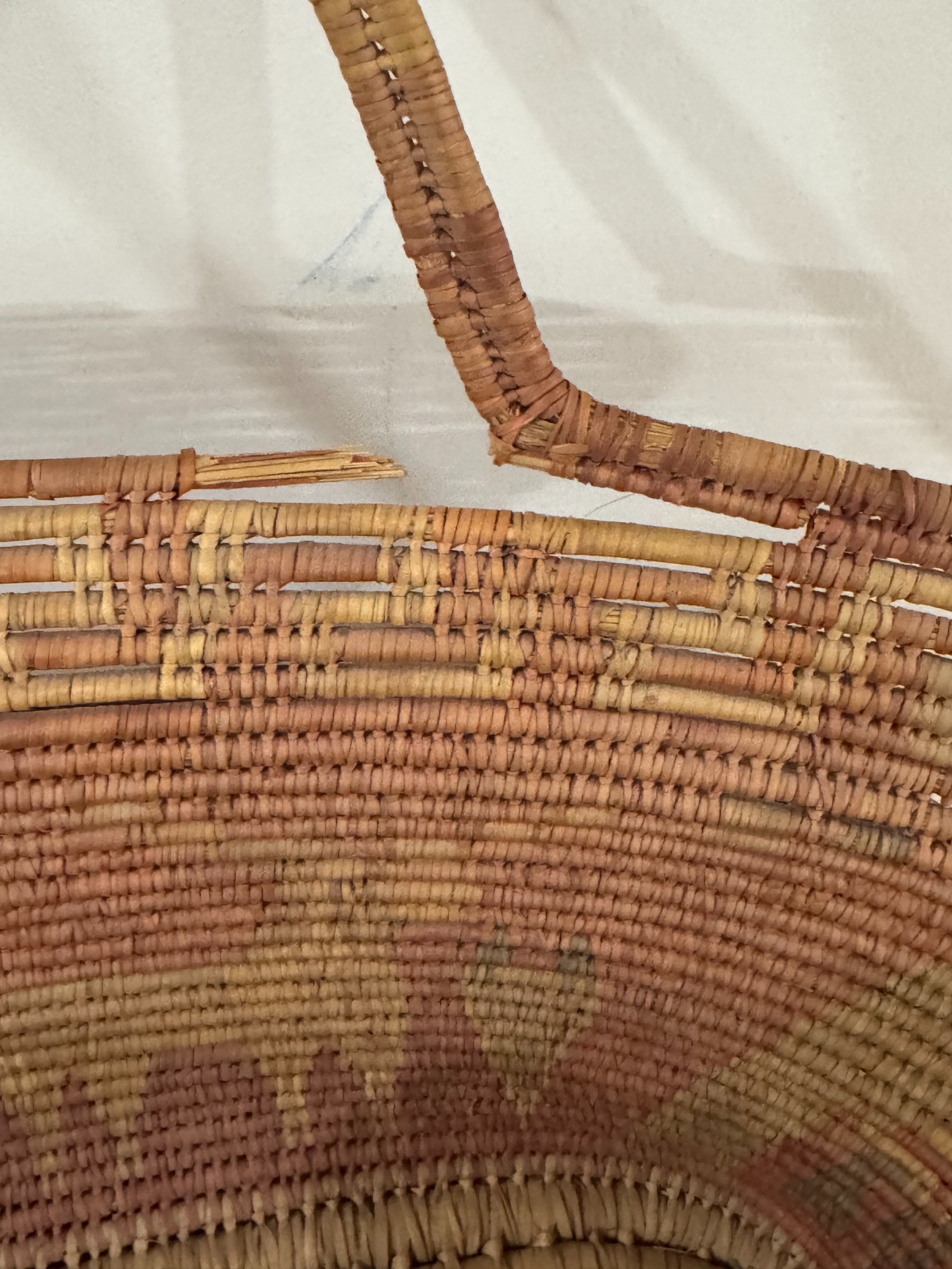 Interior detail of basket showing wrapped handle construction and horizontal weave pattern in rust and cream