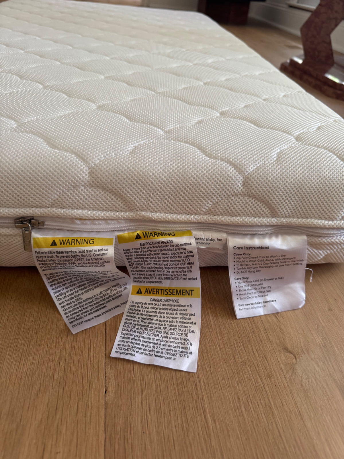 Close-up of mattress surface showing quilted texture and warning/care instruction labels attached to side