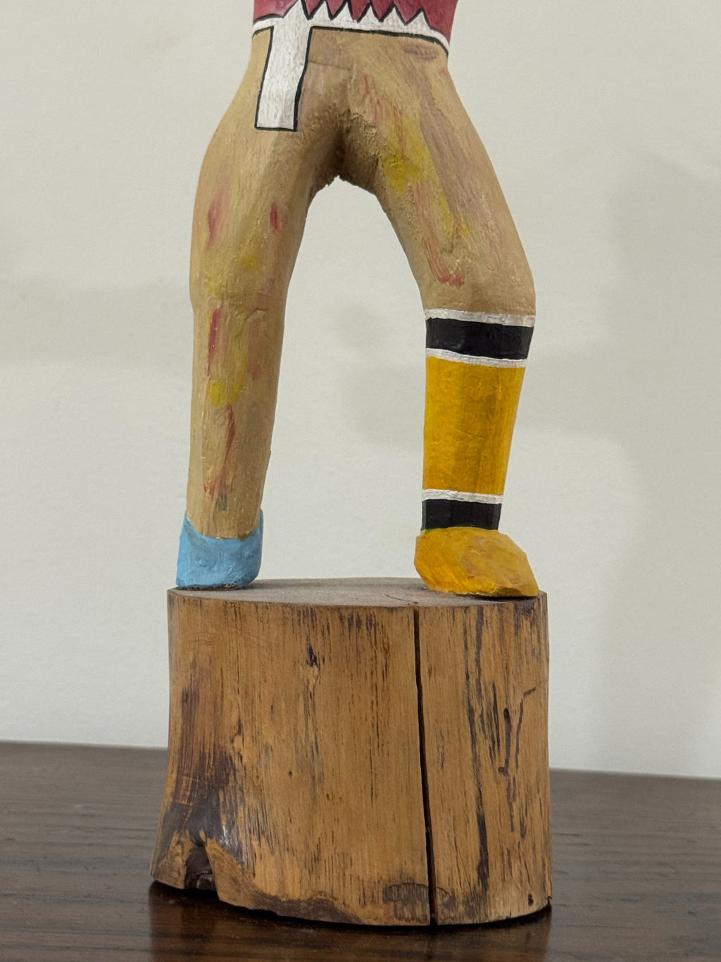 Lower body and legs showing tan wood with yellow and black striped leg wraps, white belt detail