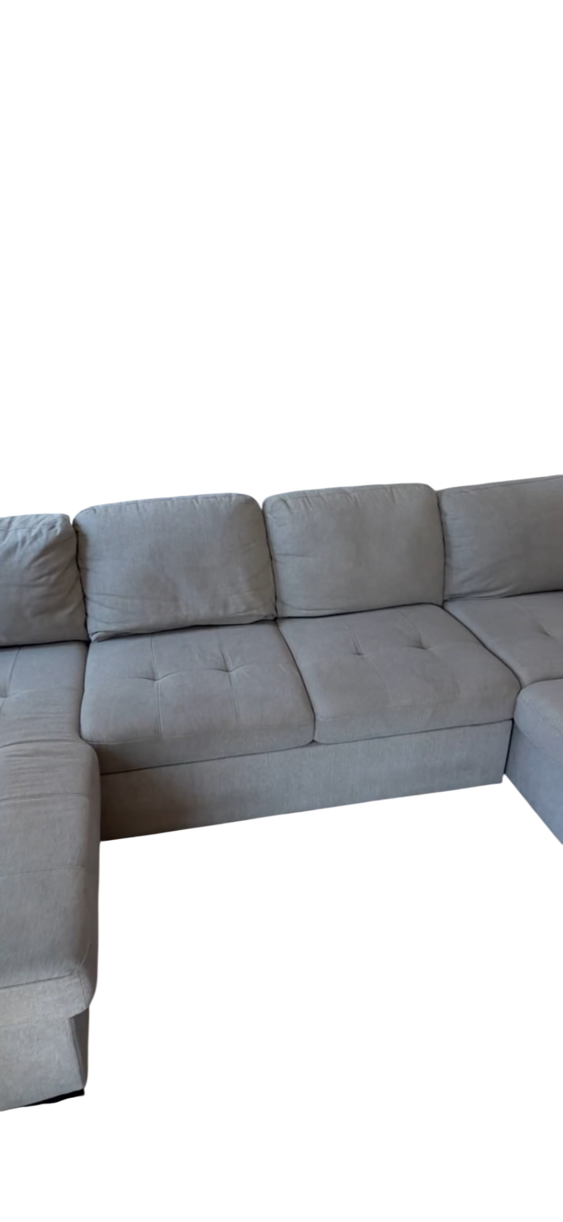 Gray upholstered L-shaped sectional sofa with tufted seat cushions, shown from side angle