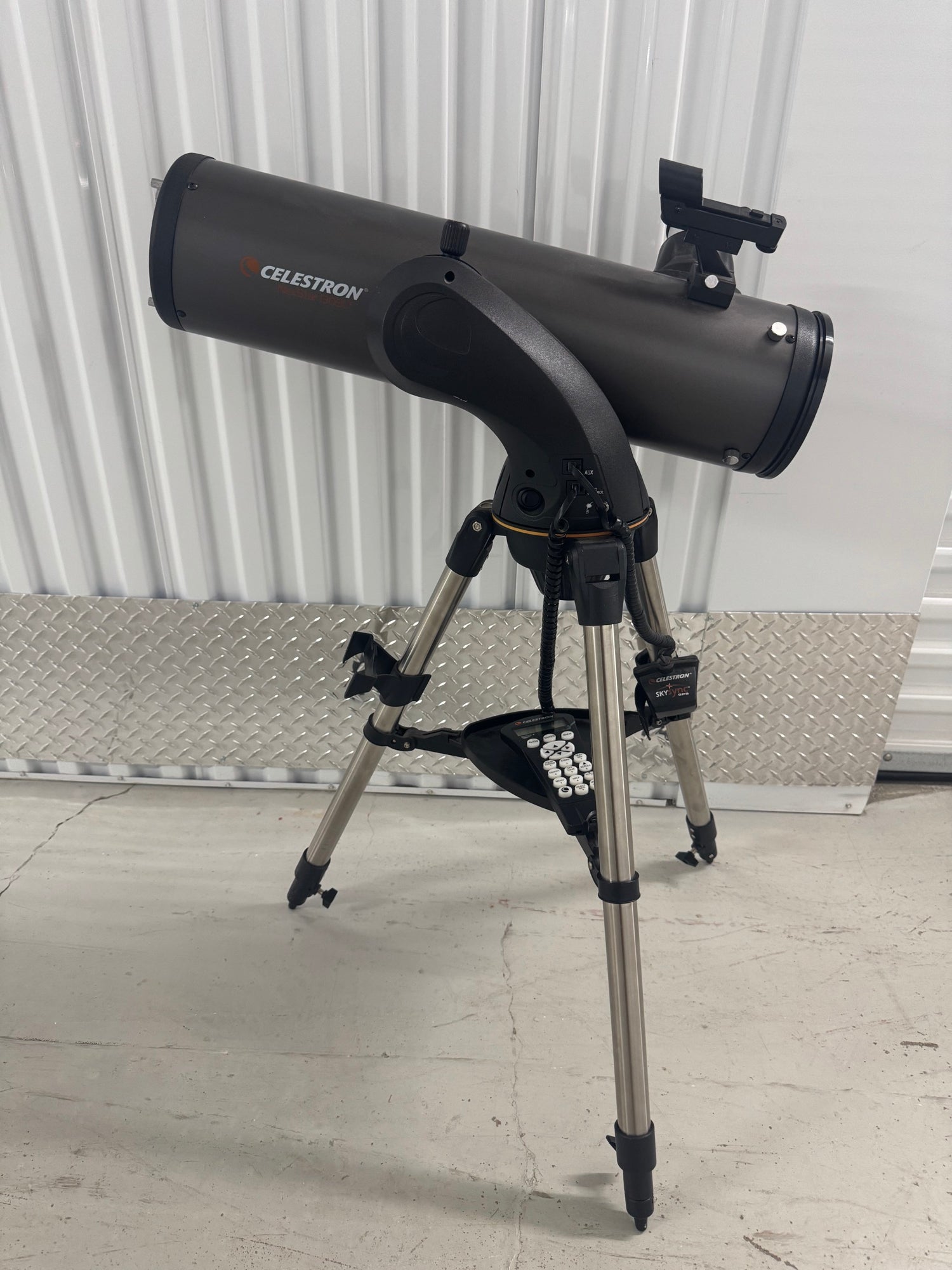 Celestron NexStar 130 SLT telescope on tripod in indoor warehouse setting with metal wall