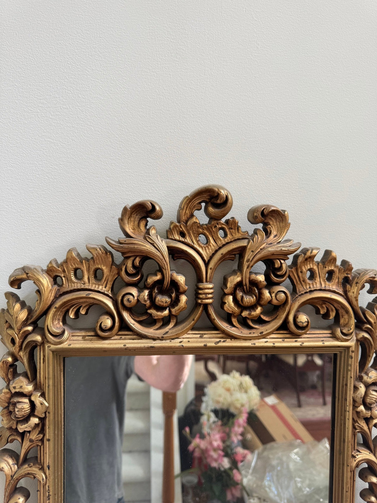 Floral and scroll crest at the top of the gilt mirror