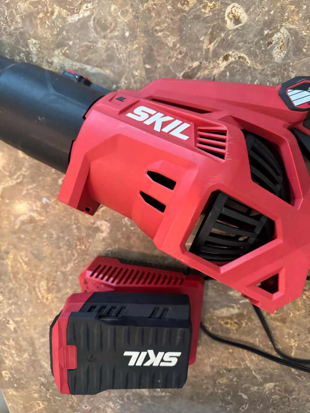 Close view of the SKIL logo on the blower housing and the battery